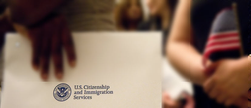 A person is holding a piece of paper with the USCIS and DHS logo in focus.