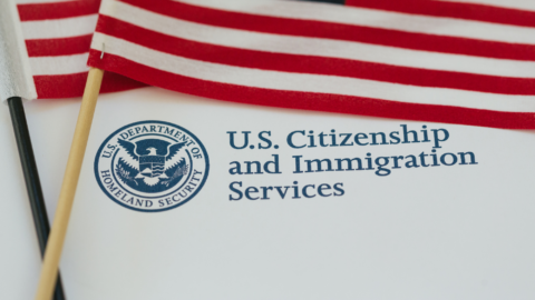 It’s a close-up of a couple of small American flags resting on a paper from the U.S. Citizenship and Immigration Services. It feels like a moment connected to immigration or citizenship.