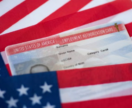 The top of a U.S. Employment Authorization Card inbetween American flags. 