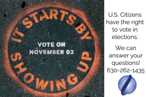 A circular, spray painted sign on the road that has orange text that says "It Starts By Showing Up" around the circular border and in white text says "Vote on November 03" in the middle. On the right-hand side, the image also says "U.S. Citizens have the right to vote in elections. We can answer your questions! 630-262-1435" With the Lentini globe logo in the bottom right-hand corner.
