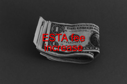 A black and white photograph of folded U.S. dollar bills with red text on top that says, "ESTA fee increase."