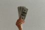 A photograph of someone holding up $100 bills fanned out.