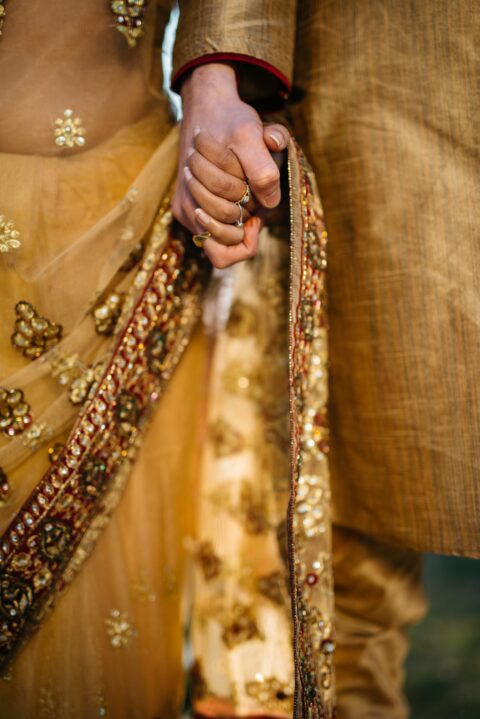Two Indian People in golden wedding clothes holding hands